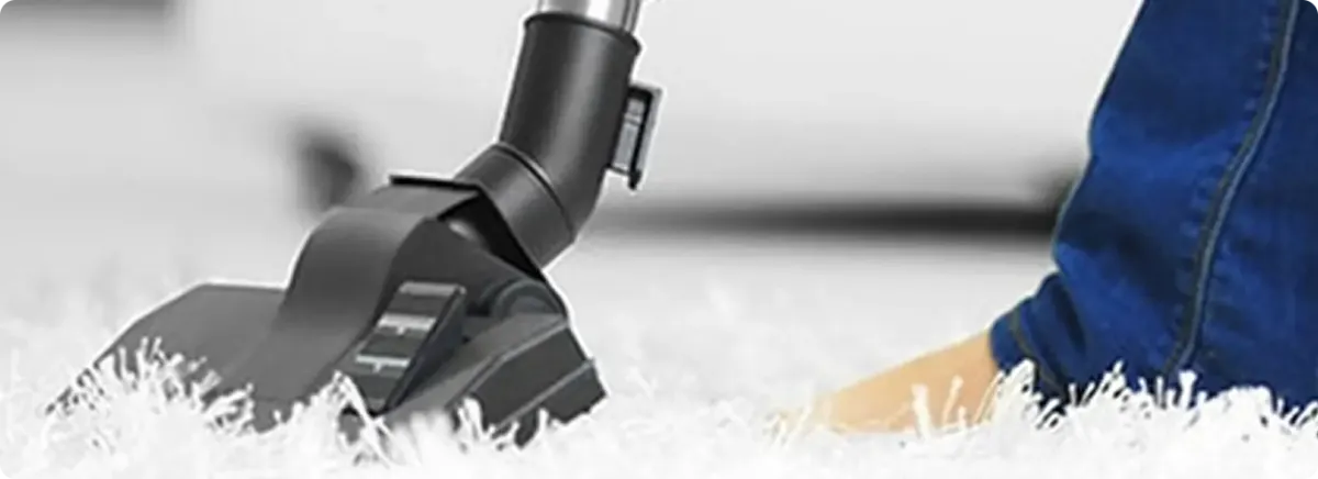 Close-up of a professional vacuuming a white carpet in Tea.
